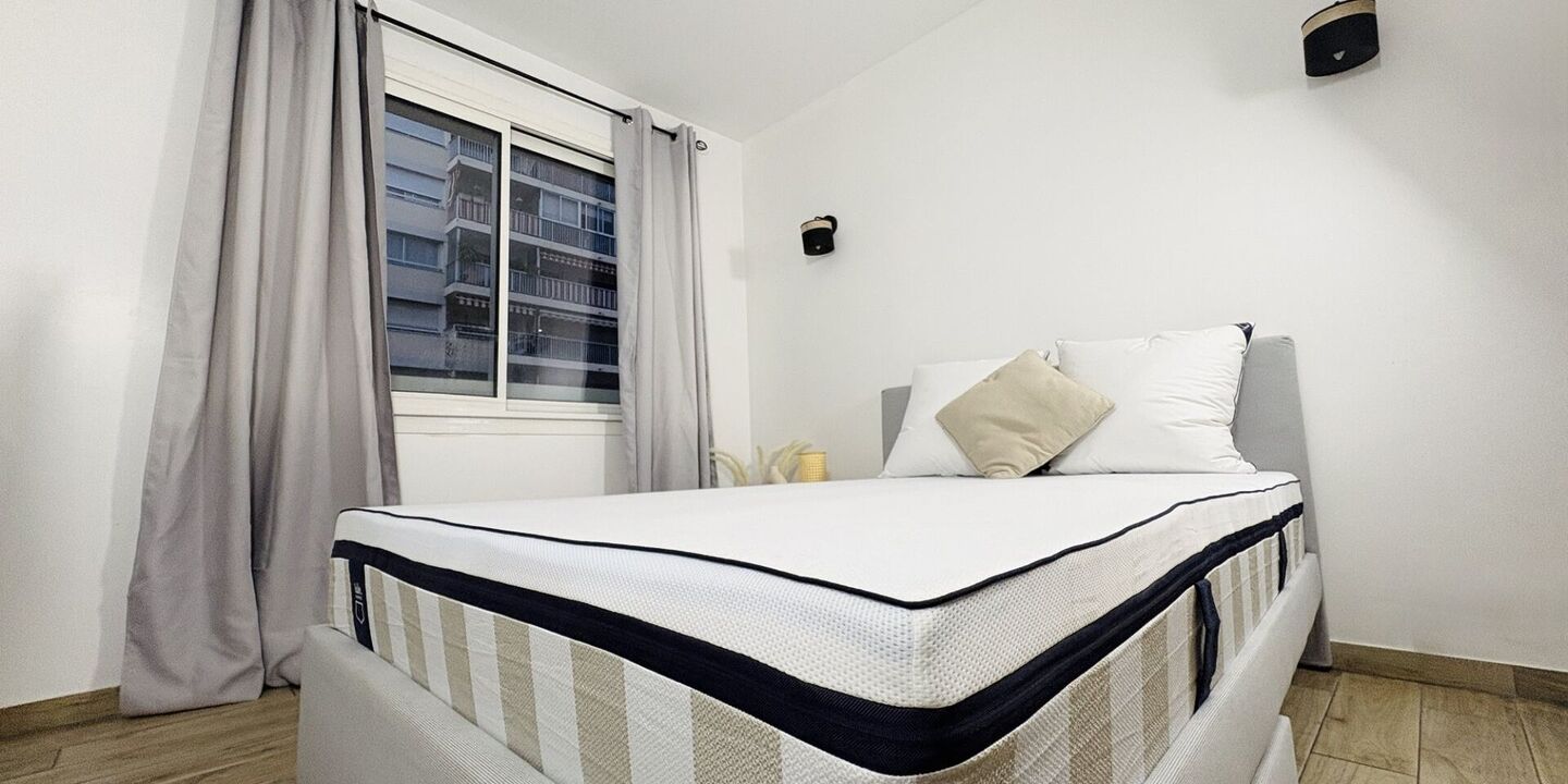 Matelas hybride à bande rayée sur un lit dans une chambre claire
