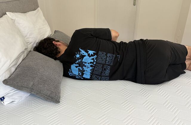 Homme endormi sur le côté, un coussin gris serré contre lui