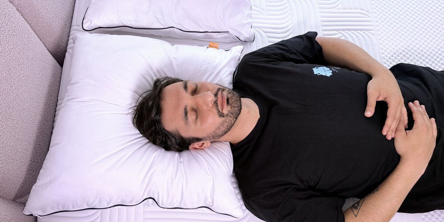 Homme endormi sur le dos, la tête calée sur un oreiller blanc, vu du dessus