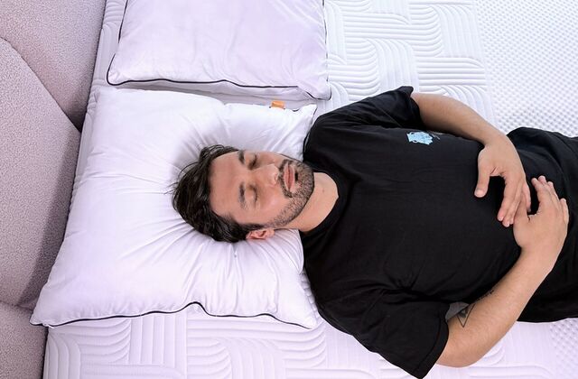 Homme endormi sur le dos, la tête calée sur un oreiller blanc, vu du dessus