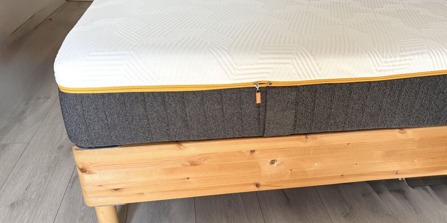 Matelas hybride gris et blanc sur un lit en pin à pieds en bois