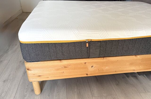 Matelas hybride gris et blanc sur un lit en pin à pieds en bois