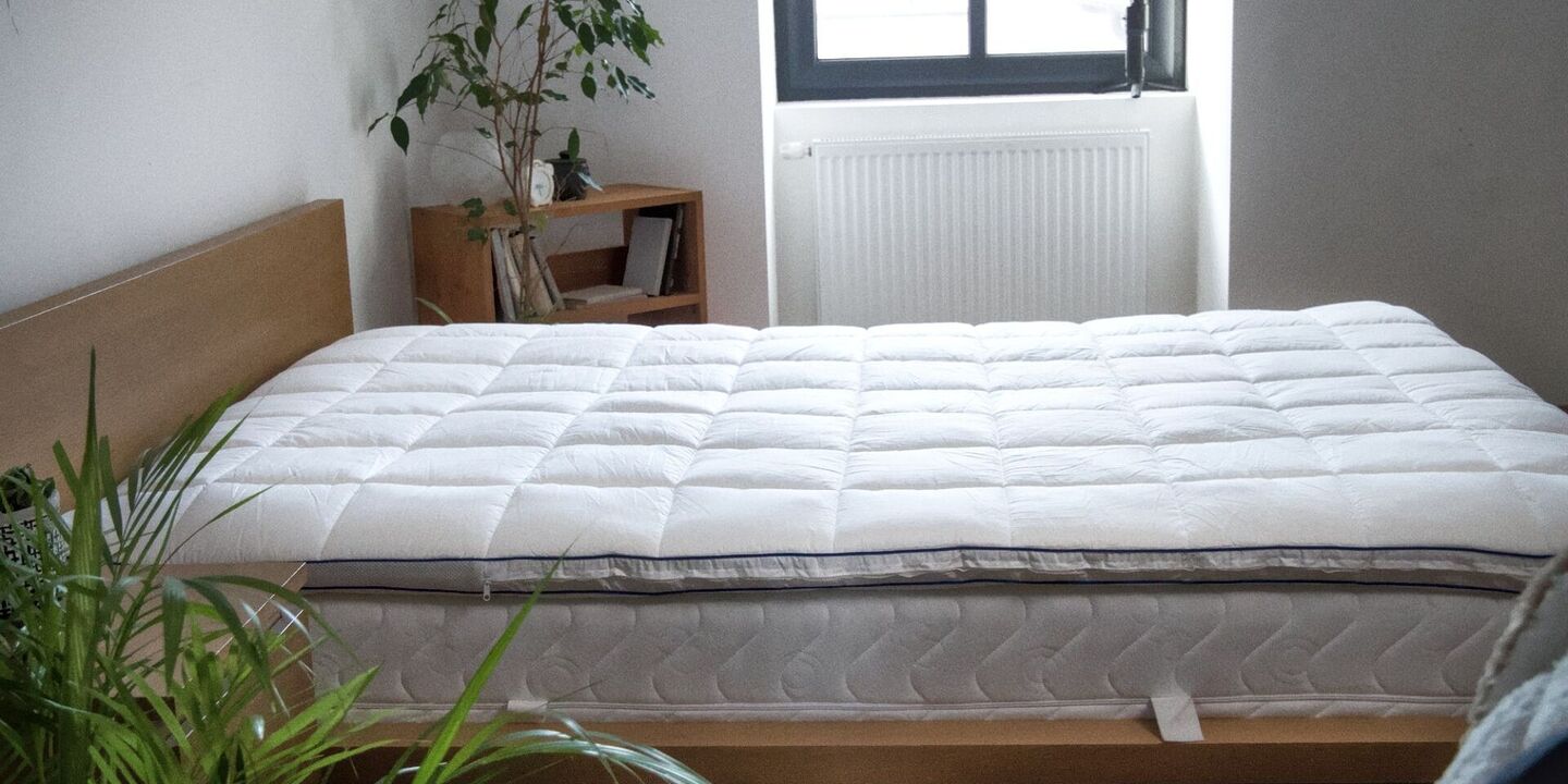 Surmatelas matelassé sur un lit en chêne près d'une fenêtre