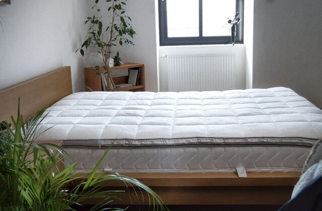 Surmatelas matelassé sur un lit en chêne près d'une fenêtre