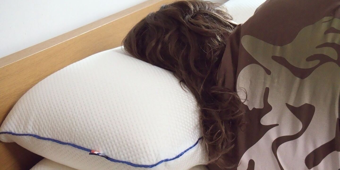 Femme endormie sur le côté sur un oreiller blanc, tête de lit en chêne