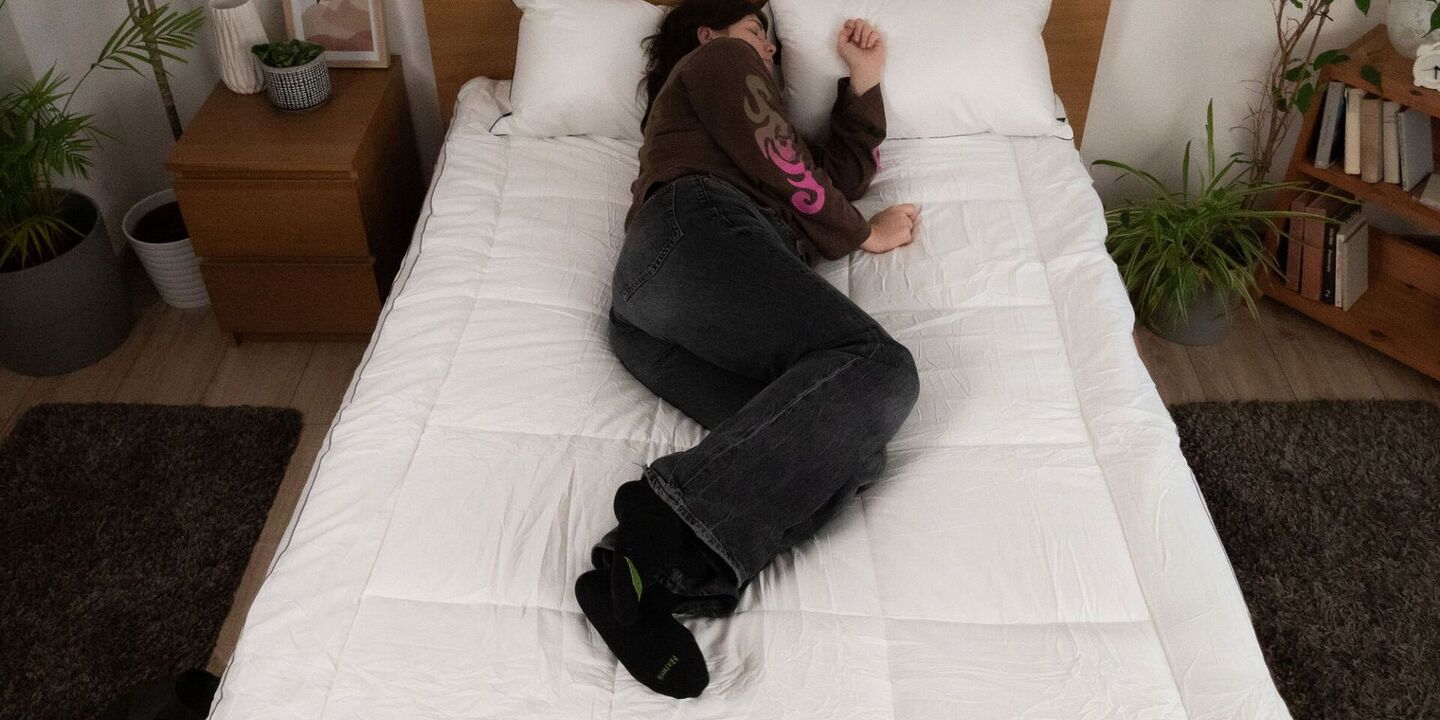 Femme recroquevillée sur le côté sur un surmatelas, vue du dessus