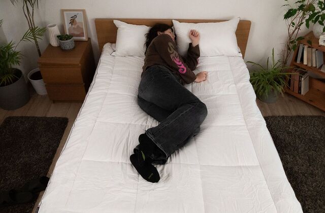 Femme recroquevillée sur le côté sur un surmatelas, vue du dessus