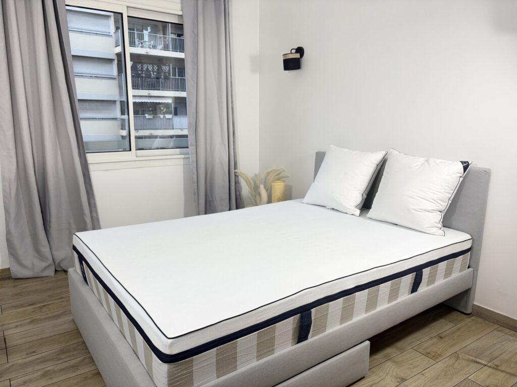 Vue d'ensemble du matelas Tediber Hybride Premium sur un lit tapissier gris