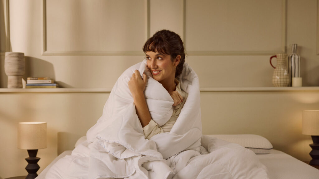 Femme enveloppée dans la Couette Emma, assise sur son lit
