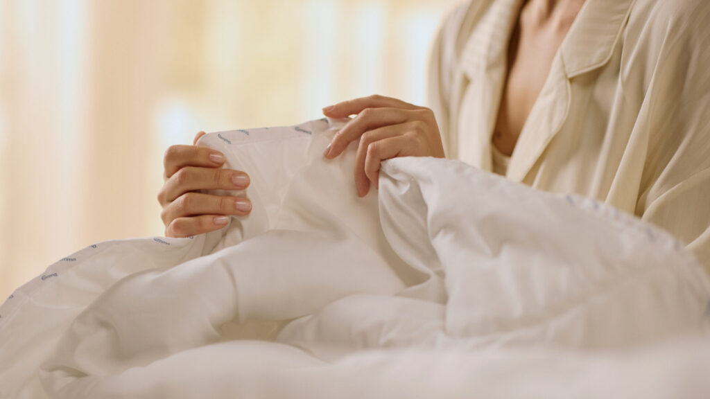Gros plan sur la bordure piquée de la Couette Emma tenue à deux mains