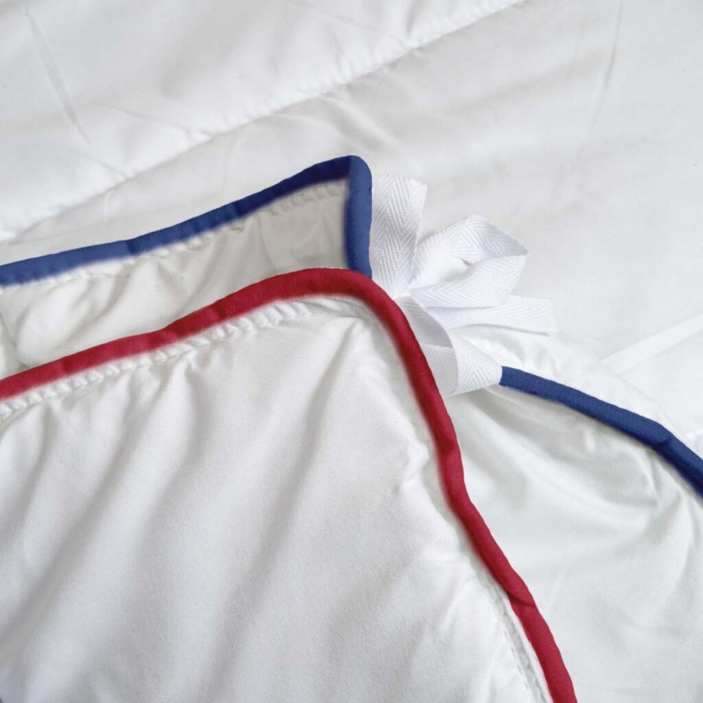 Détail des liserés bleu et rouge qui identifient les deux parties de la couette 4 saisons