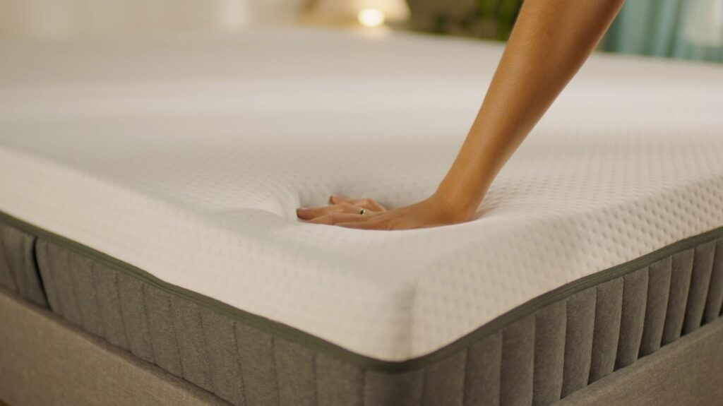 Main appuyée sur la housse du matelas Emma Original Lite