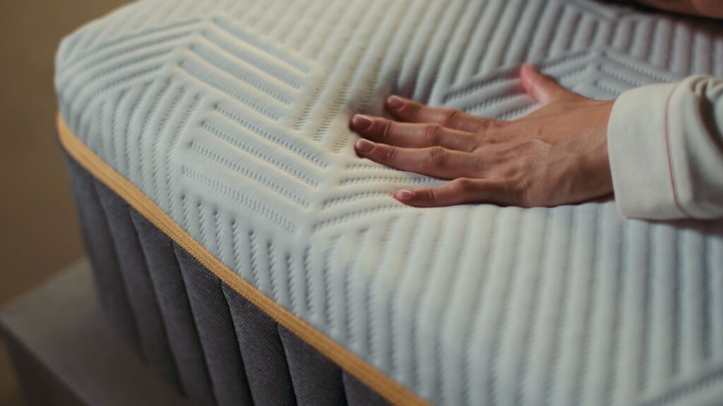 Main posée sur la housse premium du matelas Emma Original Pro