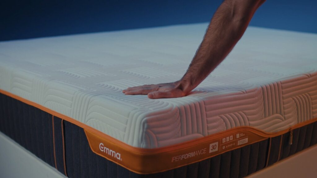 Main appuyée sur la housse d'un matelas Emma Performance