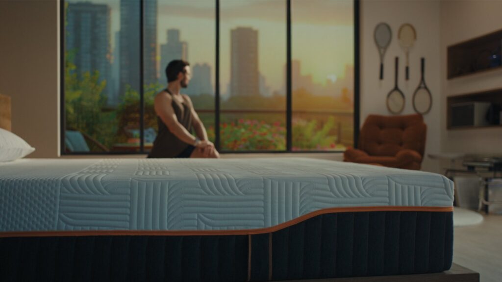 Homme assis au bord d'un matelas Emma Performance dans une chambre
