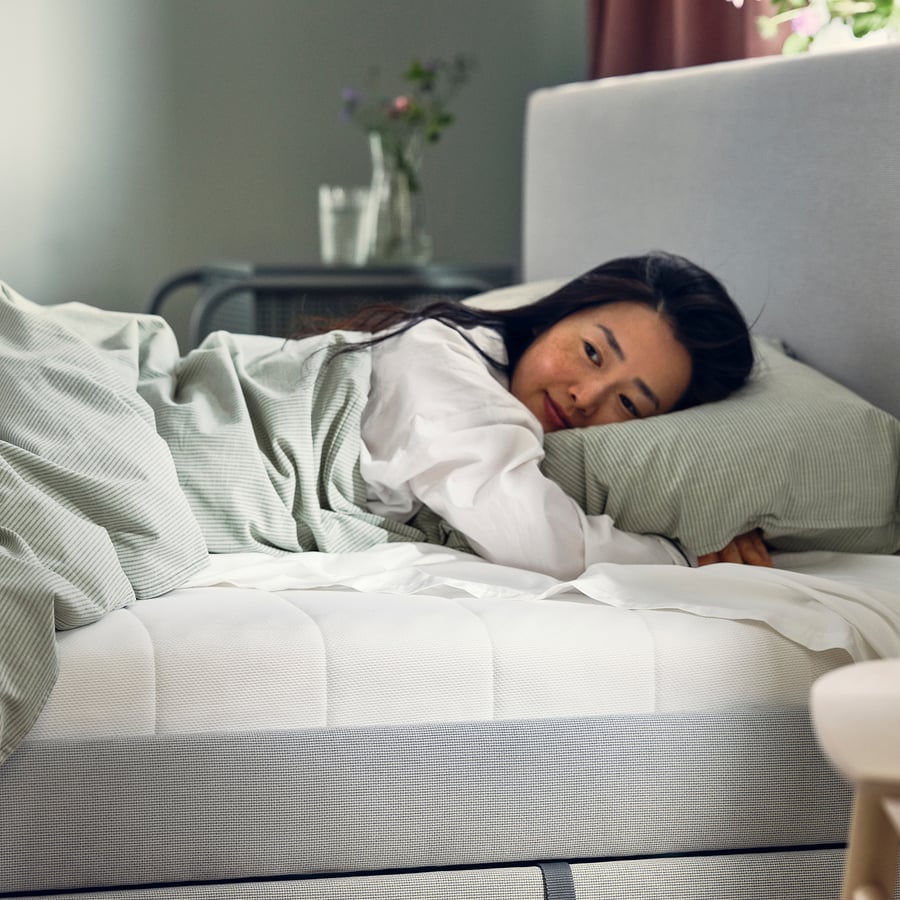 Femme allongée sur un matelas IKEA ÅFJÄLL dans une chambre