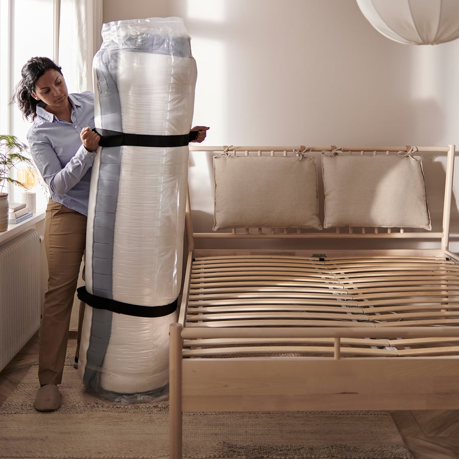 Matelas IKEA VALEVÅG livré roulé, déballage près du lit