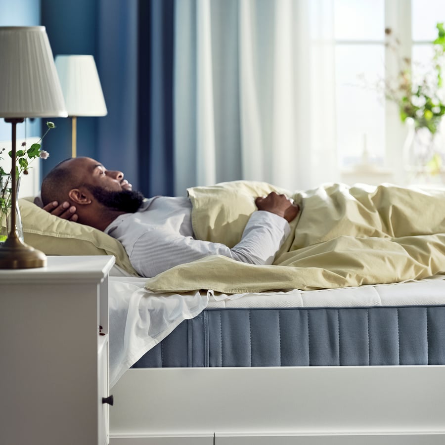 Homme endormi sur un matelas IKEA VESTERÖY dans une chambre