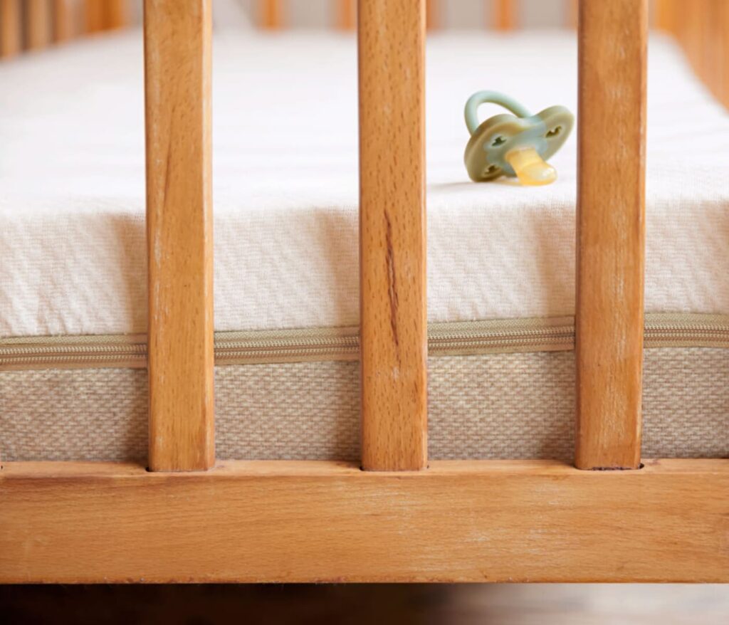 Matelas bébé Kipli Essentiel dans un lit à barreaux en bois