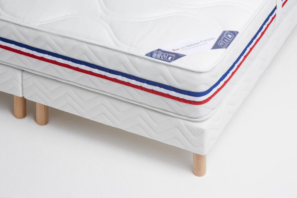 Matelas Philibert posé sur un sommier tapissier à pieds en bois, vue d'angle