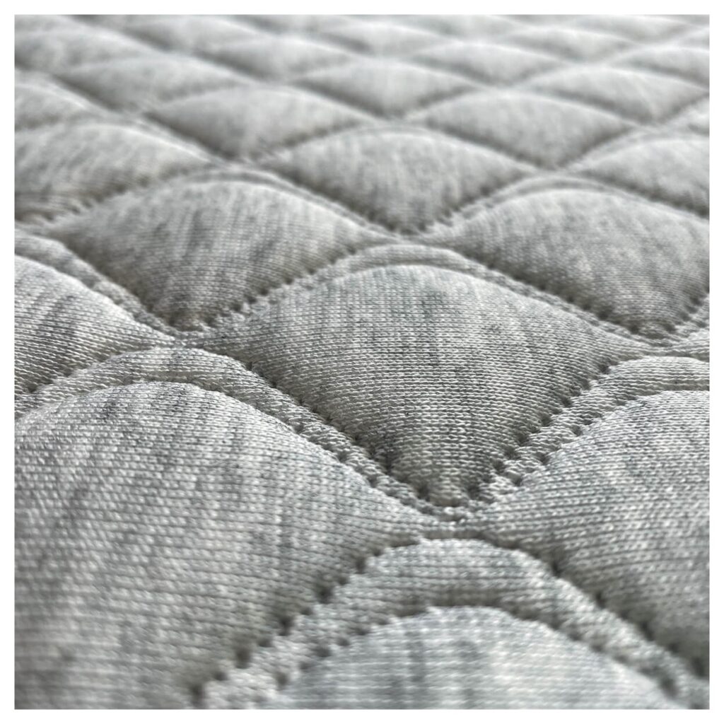 Gros plan du coutil matelassé gris du matelas Candide Résilience