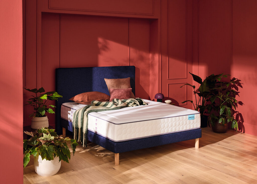 Matelas Mérinos Beauty Bed sur un lit à tête de lit bleue dans une chambre rouge