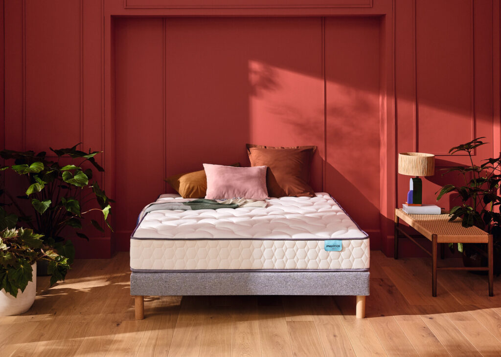 Matelas Mérinos Cosy Lit sur un sommier gris dans une chambre rouge brique