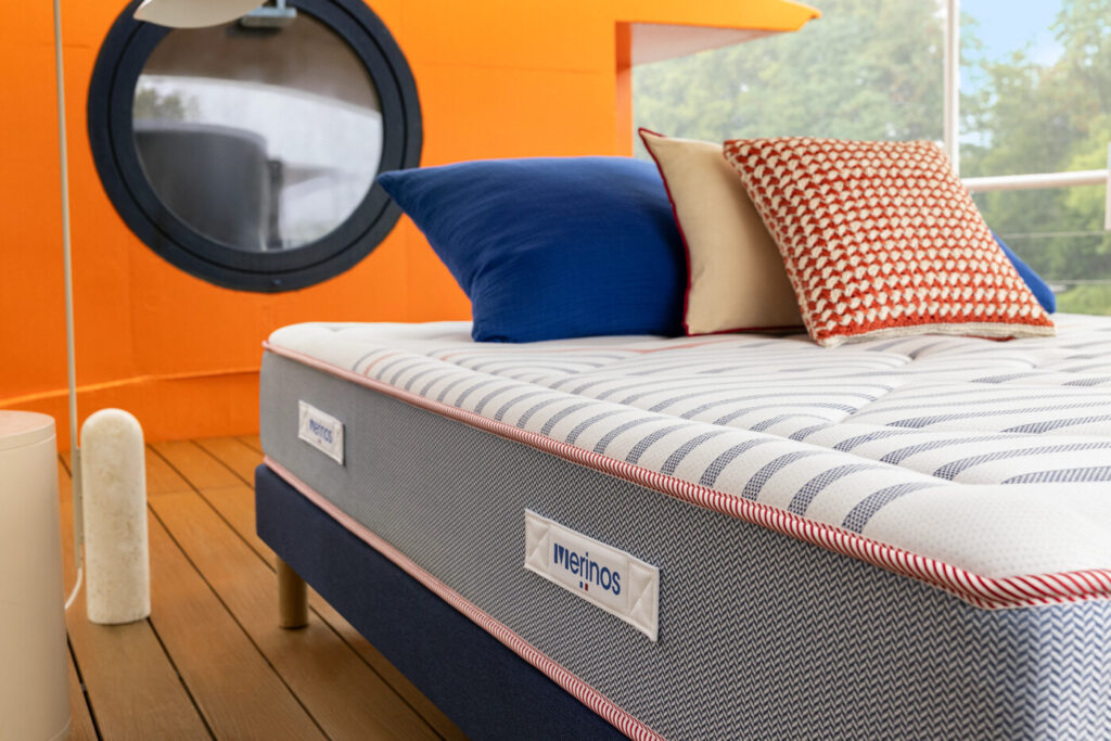 Matelas Mérinos Marinière Iconique sur un sommier bleu marine, coussins rayés