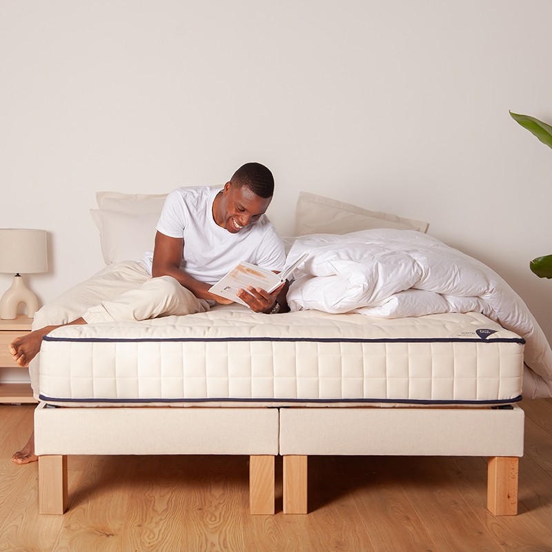 Homme lisant sur le matelas Cosme Très Ferme