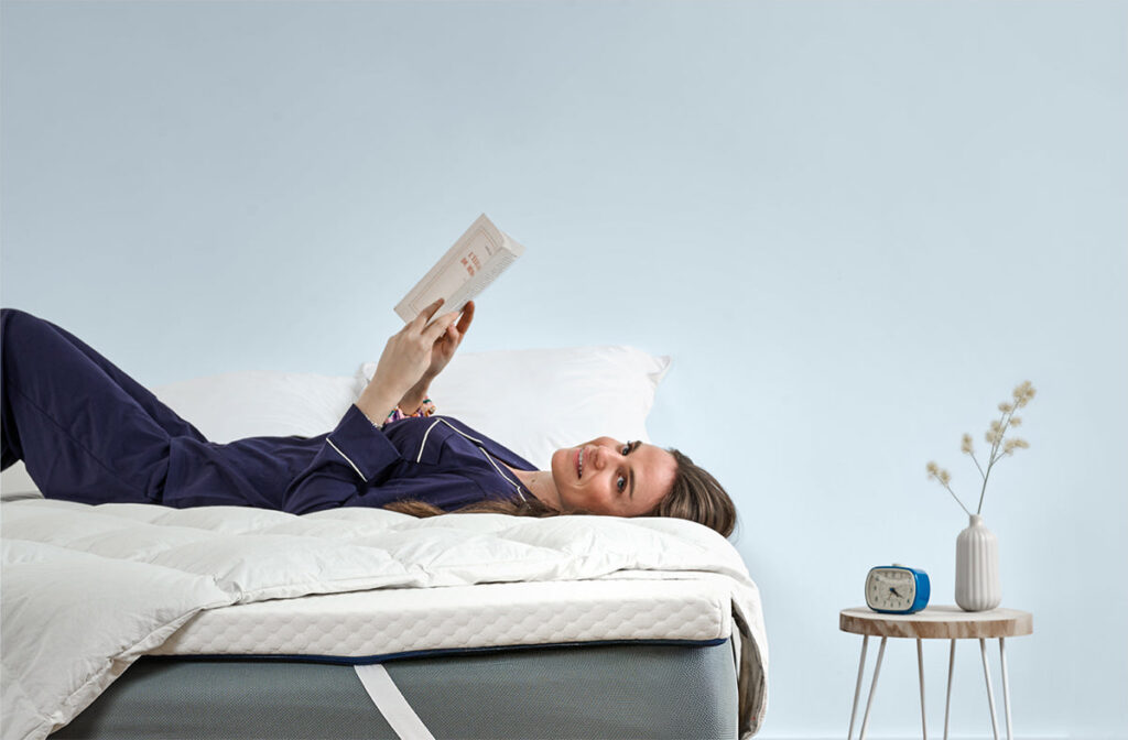 Surmatelas Nyte Cosy sur un lit avec couette et oreillers, chambre bleu clair