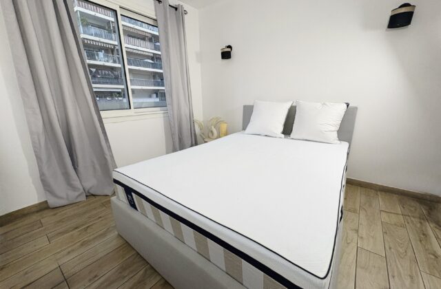 Lit avec matelas dans une chambre, fenêtre et rideaux