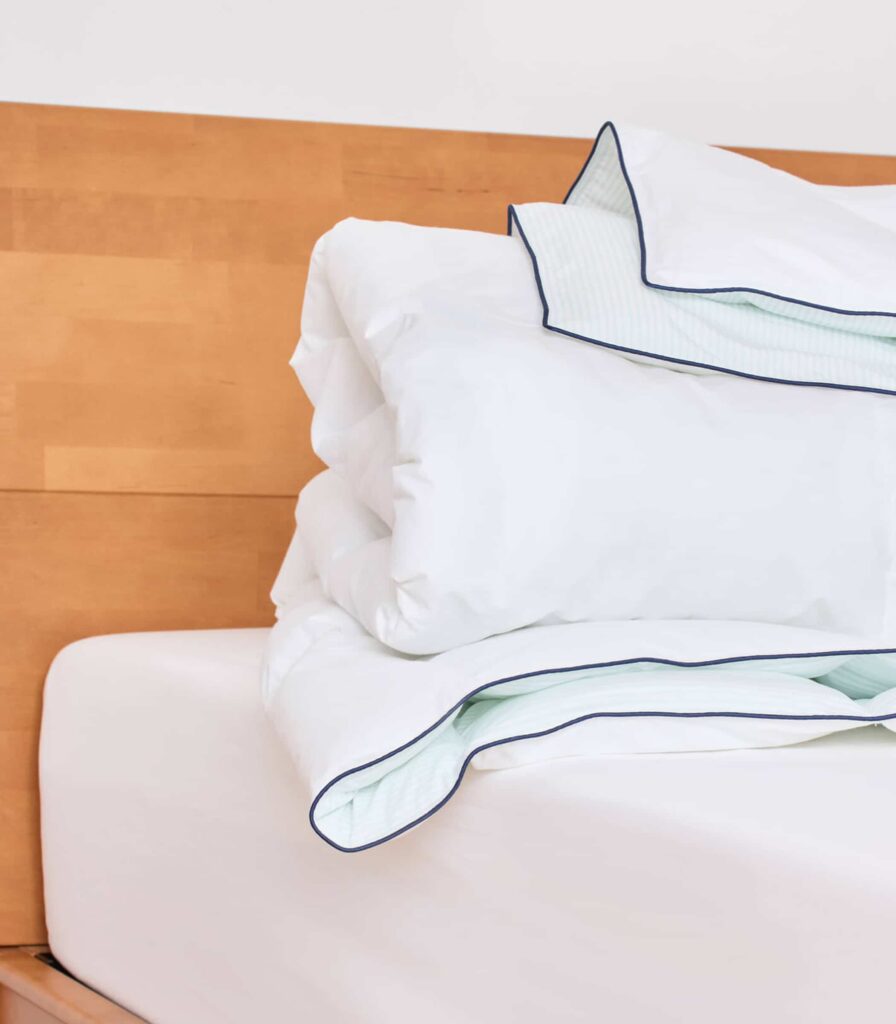 Couette tempérée Plus Tediber posée sur un lit en bois