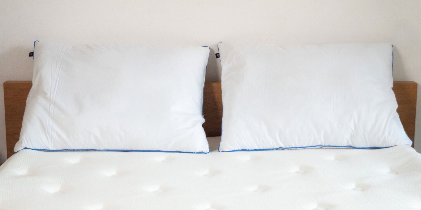 Deux oreillers blancs contre une tête de lit en chêne