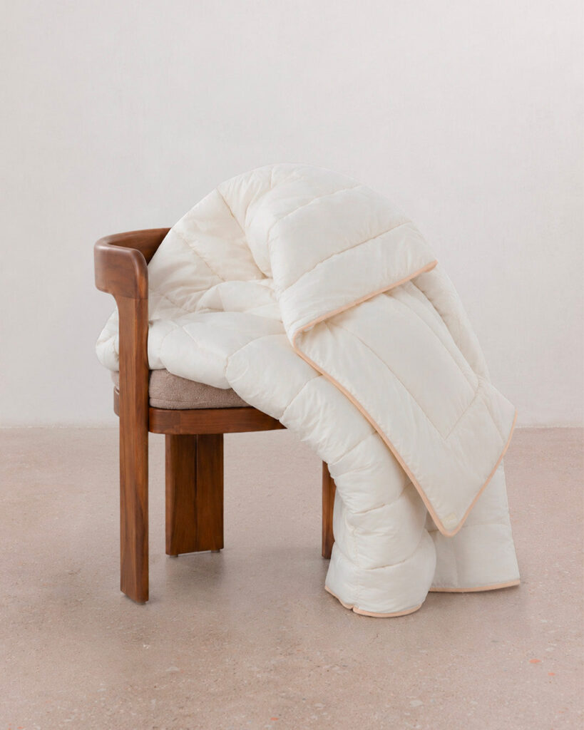 Couette Hiver Drimz pliée sur une chaise en bois, liseré beige