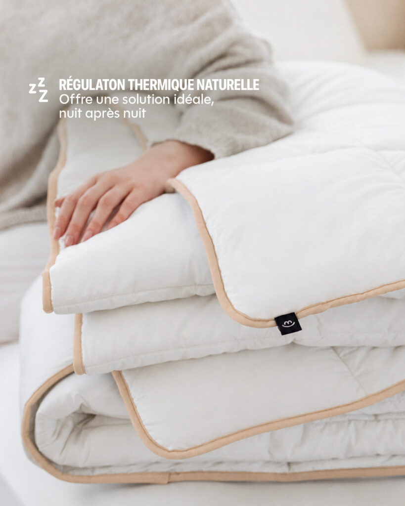 Main posée sur la couette Drimz repliée sur un lit