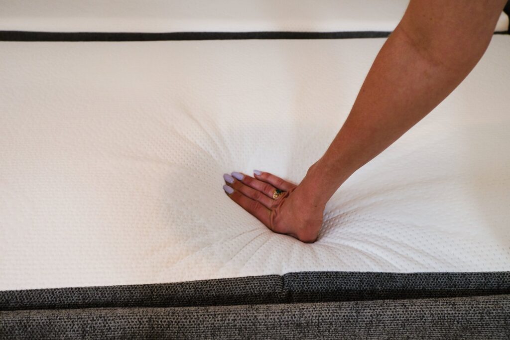Main appuyant sur le matelas du canapé convertible Emma Original