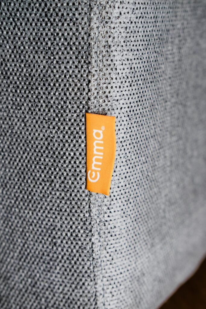 Gros plan sur le tissu et l'étiquette Emma du canapé convertible Original