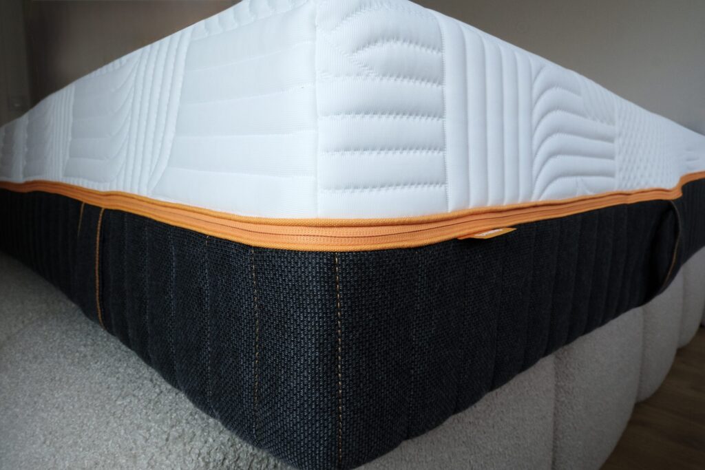 Flanc du matelas Emma Performance posé sur un lit en bouclette