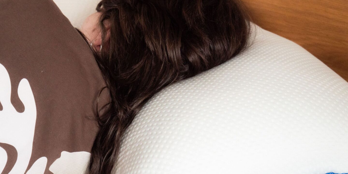 Femme allongée, la tête posée contre un oreiller blanc
