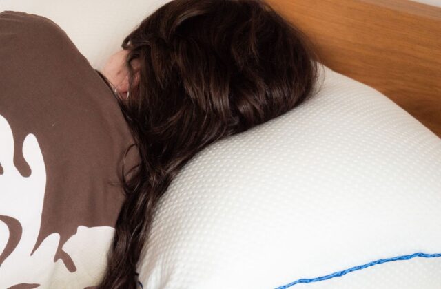 Femme allongée, la tête posée contre un oreiller blanc