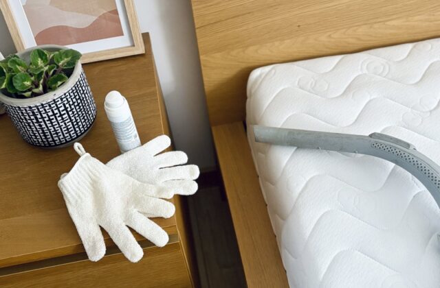 Gants de nettoyage et tuyau d'aspirateur sur un matelas matelassé