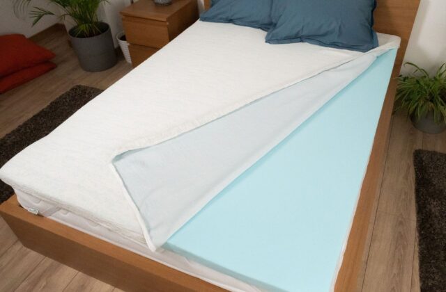 Housse repliée révélant la mousse bleue d'un surmatelas sur le lit