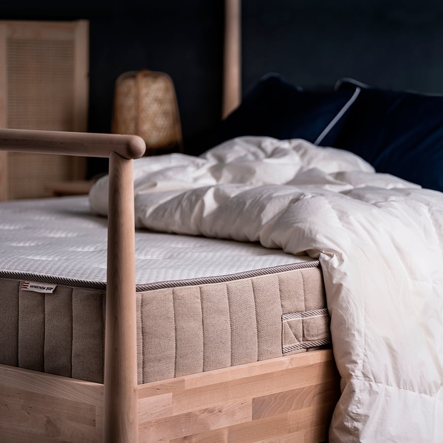Matelas IKEA VATNESTRÖM sous une couette dans une chambre aux tons sombres