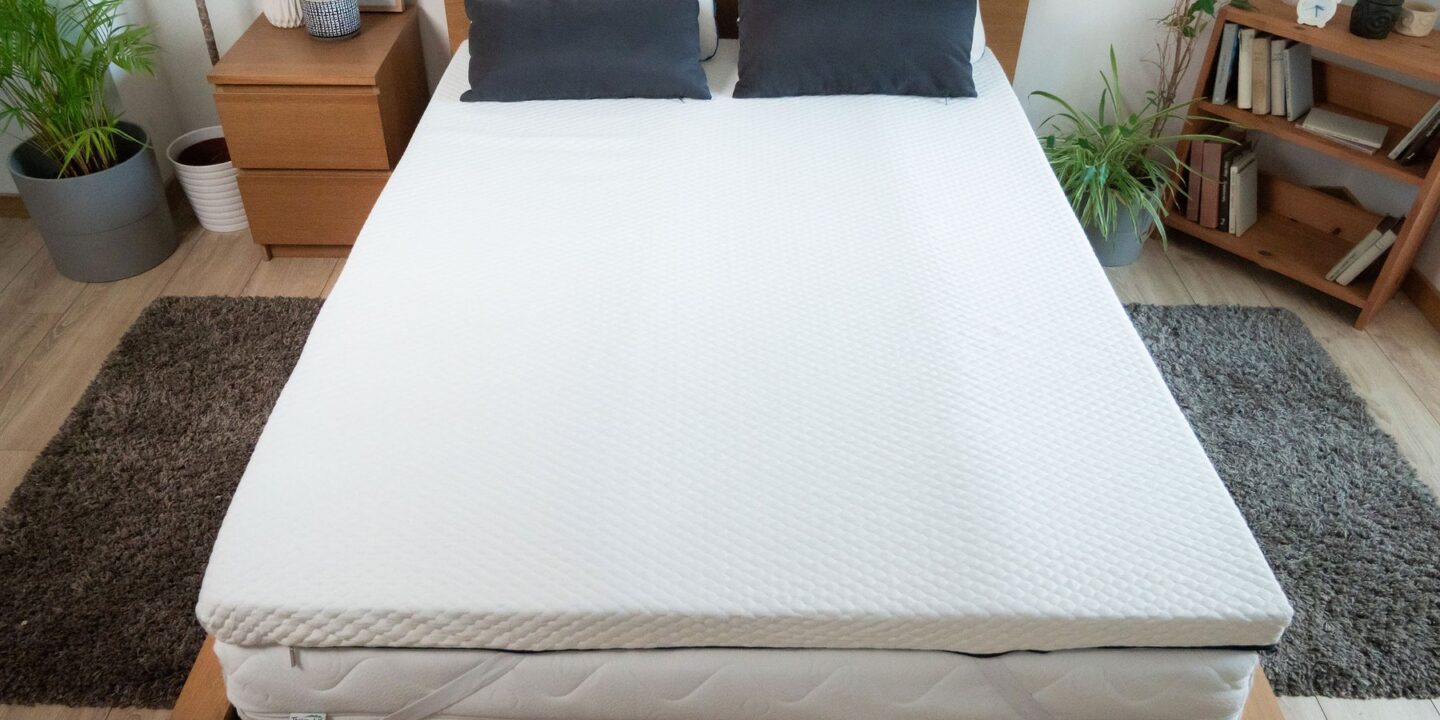 Lit avec surmatelas et coussins sombres, vu de face