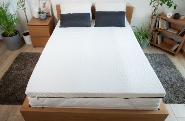 Lit avec surmatelas et coussins sombres, vu de face