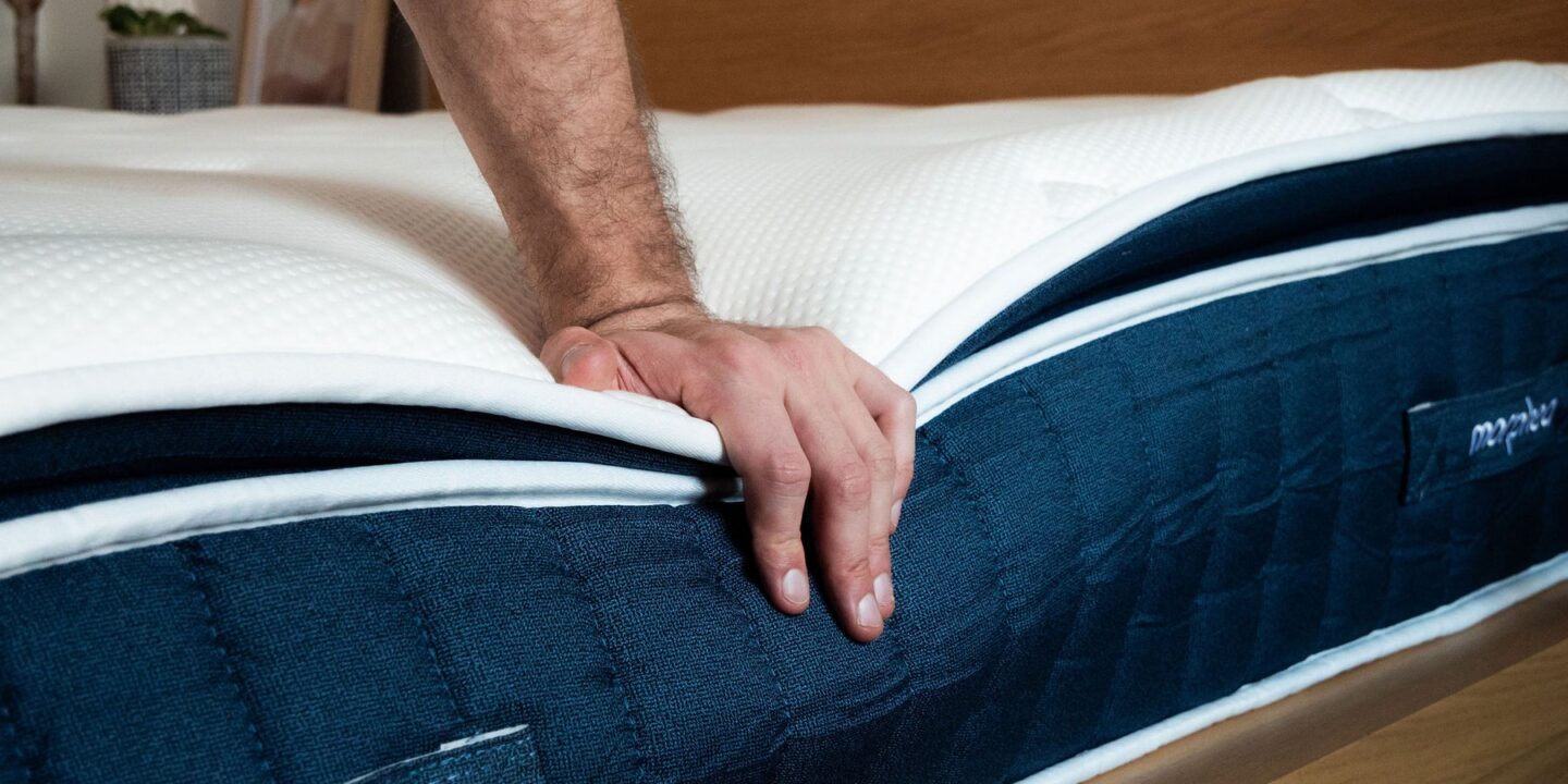 Main appuyant sur le bord d'un matelas pour tester sa fermeté