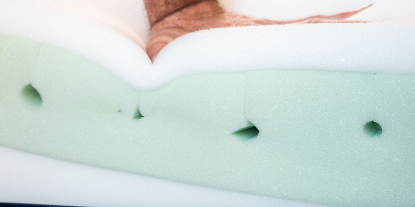 Main appuyant sur la mousse d'un matelas sans housse