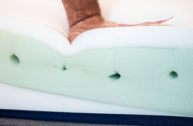 Main appuyant sur la mousse d'un matelas sans housse