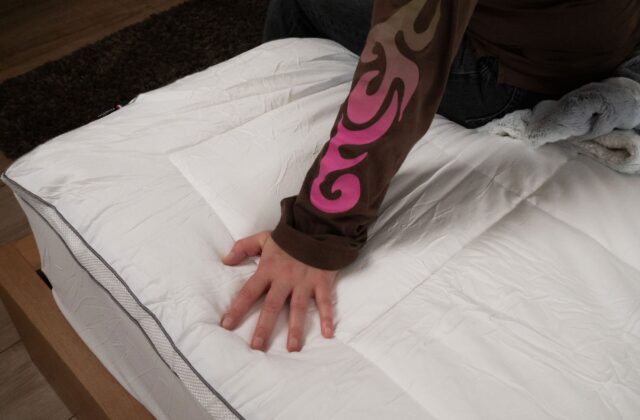 Personne appuyant la main sur un surmatelas matelassé