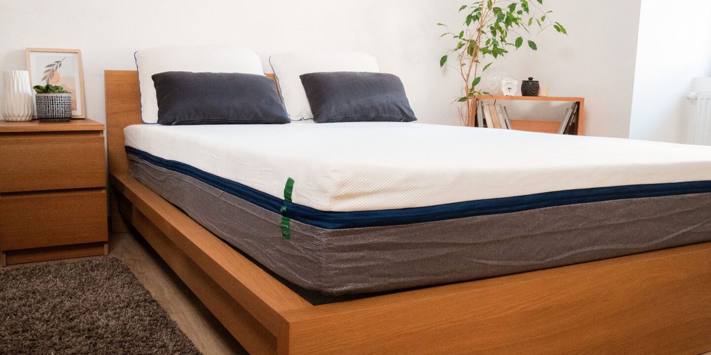 Vue latérale d'un matelas avec oreillers sur un lit en chêne